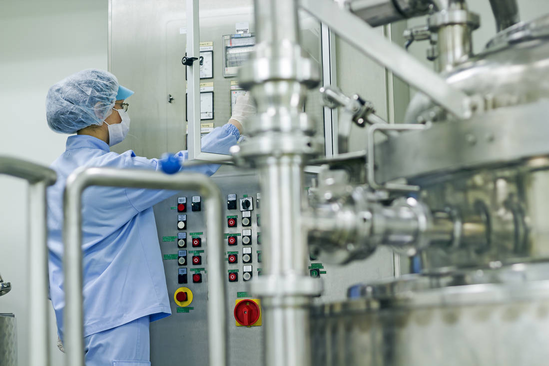 Mitarbeiterin bedient das Bedienpanel einer pharmazeutischen Maschine